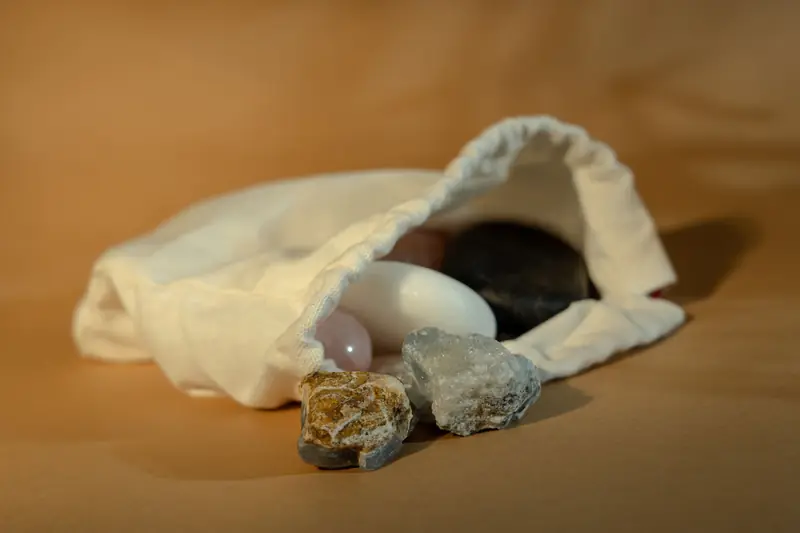 Close-up view of various stones in a white cotton bag on a brown surface